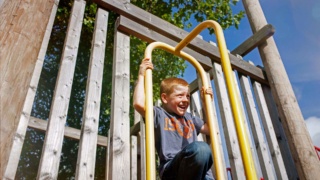 Boy playing outside in the park on a jungle gym