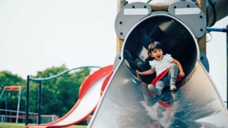 Toddler girl going down a playground slide