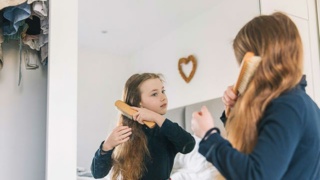 Pre-teen girl brushing her hair in a mirror