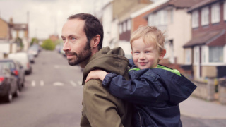 Young son on father's back doing the school run