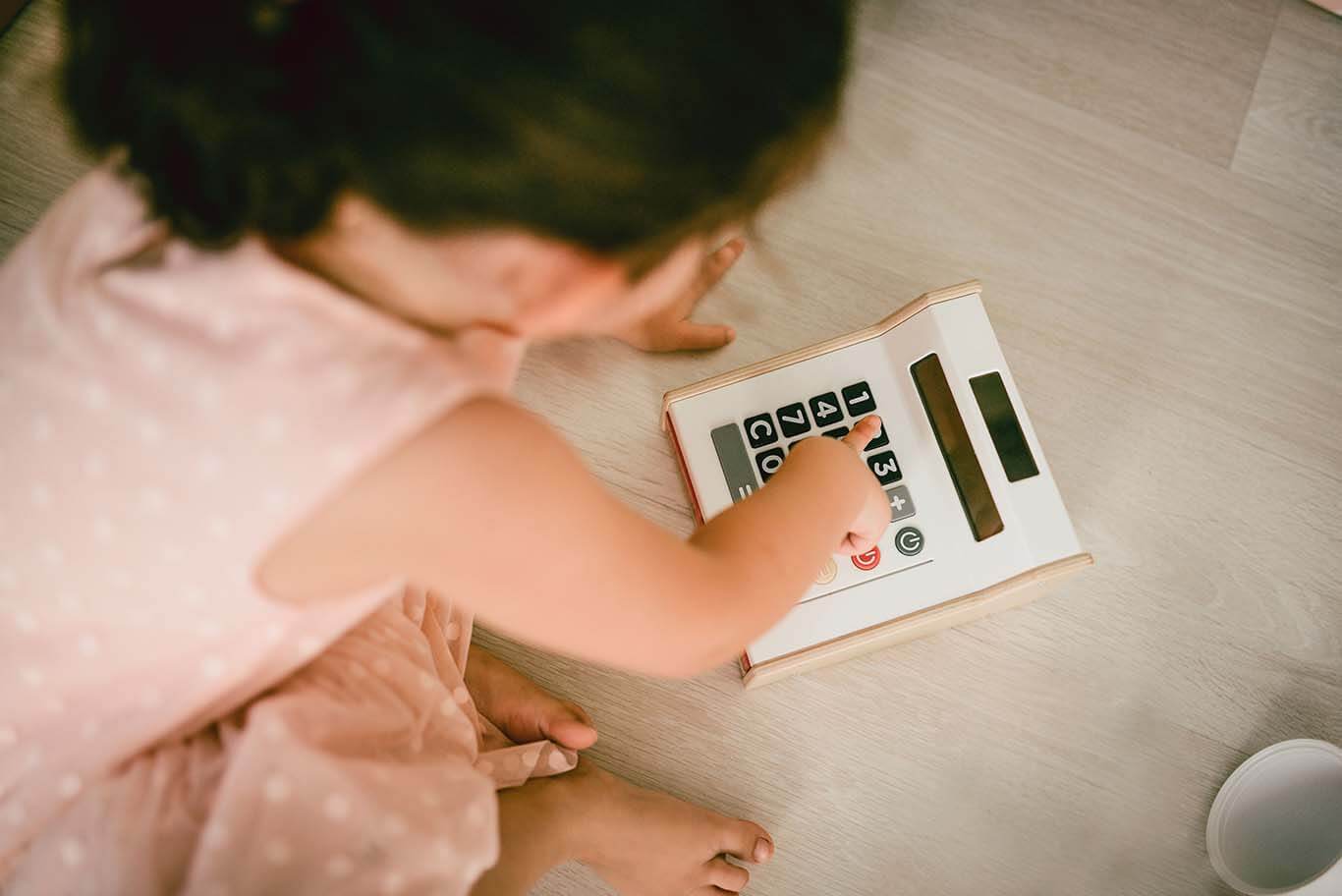 Little girl typing numbers on calculator